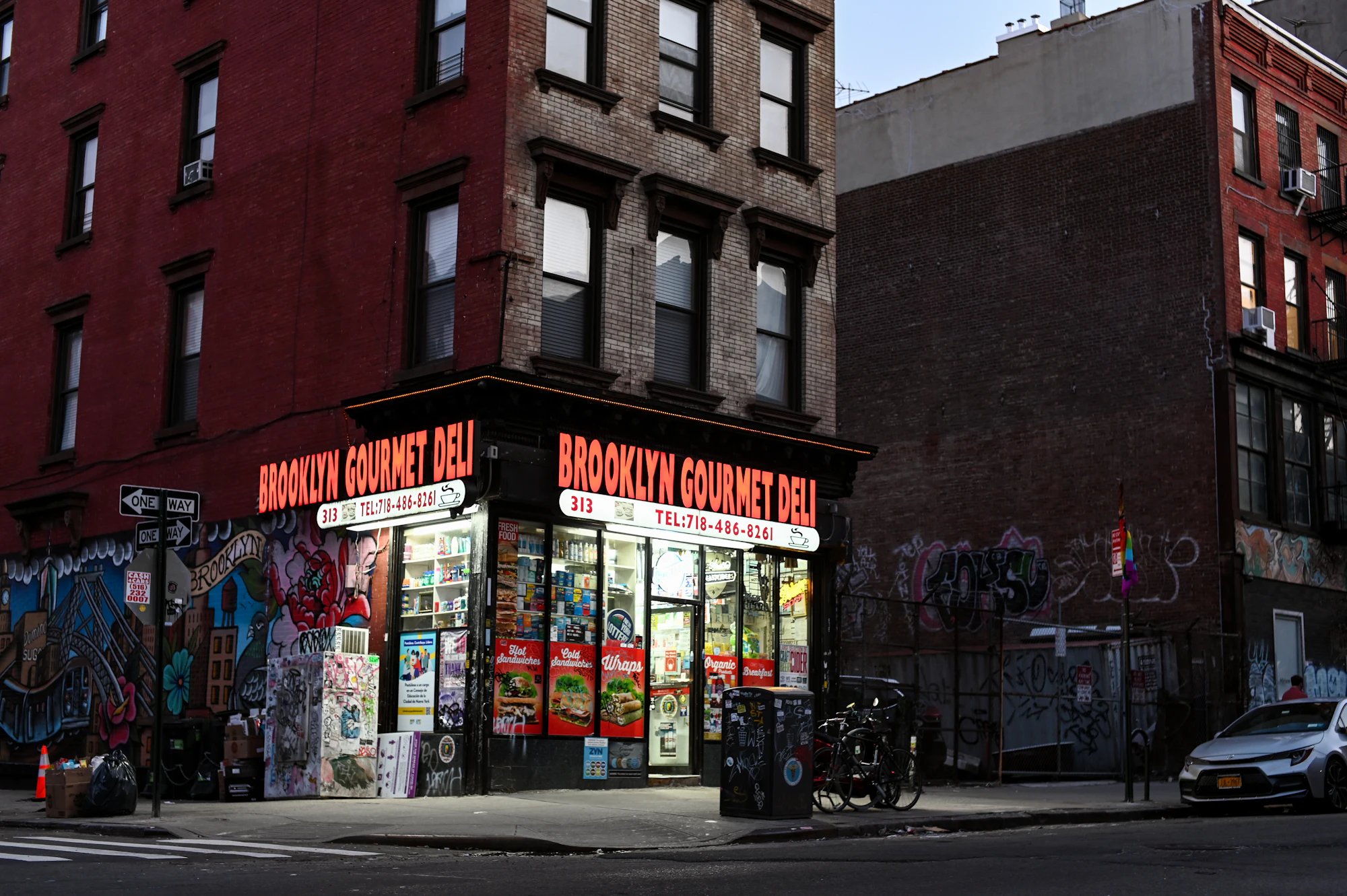A corner deli on the ground floor of a red brick building on a Brooklyn street.